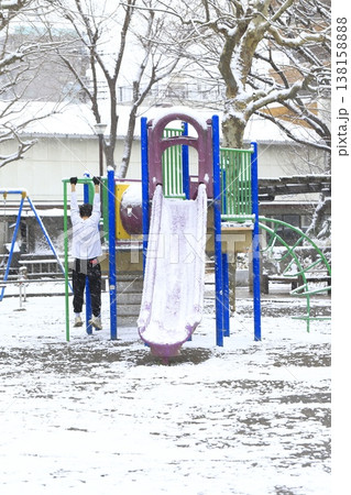 雪の降る日の公園と遊具で遊ぶ子供 138158888