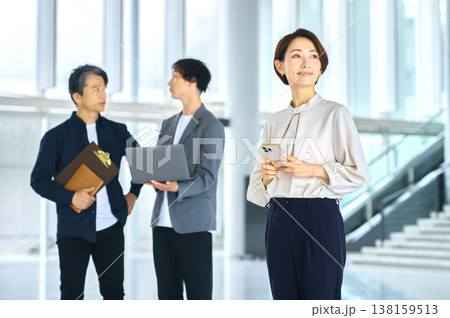 明るいオフィスでスマートフォンを持つ笑顔のビジネス女性と働くチーム 138159513