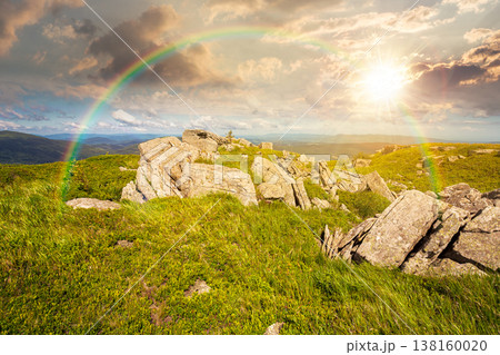 grassy alpine meadow in carpathian mountain landscape at sunset. sharp rocks and huge boulders among green grass on rolling hills in evening light. open space scenery for wanderlust and exploration 138160020