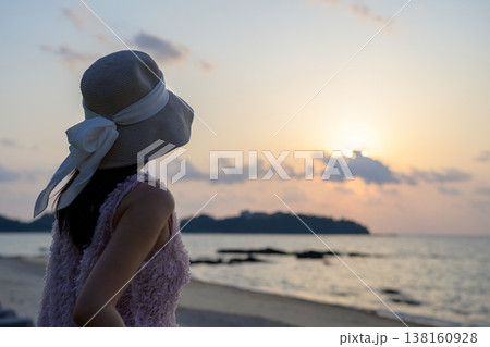 沖縄のビーチで夕焼けを眺める日本人女性 沖縄のビーチで夕焼けを眺める日本人女性 138160928