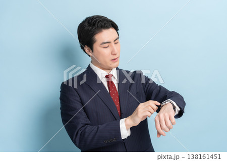 時計を見るビジネスマン男性（ブルーバック） 138161451