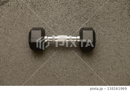 Single black dumbbell on textured surface for fitness and strength training 138161969