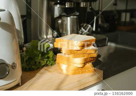 Stack of white bread slices with lettuce on kitchen counter in sunlight Stack of white bread slices with lettuce on kitchen counter in sunlight 138162000