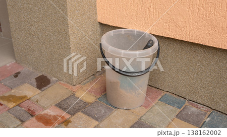 Plastic bucket with handle on colorful paved patio Plastic bucket with handle on colorful paved patio 138162002