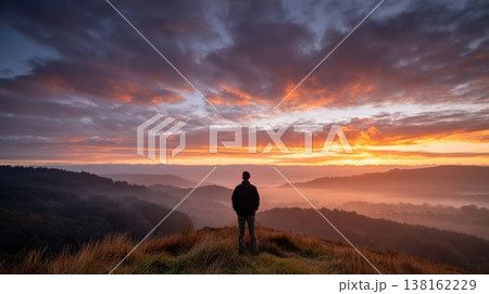 Lone person watching dramatic sunrise over misty hills for motivational background and landscape banner design Lone person watching dramatic sunrise over misty hills for motivational background and landscape banner design 138162229