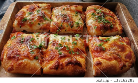Baked cheesy bread squares on tray with herb garnish for recipe banner menu presentation and family serving inspiration 138162295
