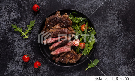 Grilled beef steak with spices on a black plate Grilled beef steak with spices on a black plate 138162556
