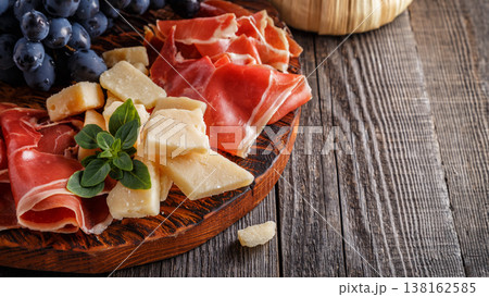 Prosciutto, wine, grape, parmesan on wooden table. 138162585