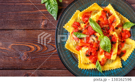 Ravioli with tomato sauce and basil on dark background. Ravioli with tomato sauce and basil on dark background. 138162596