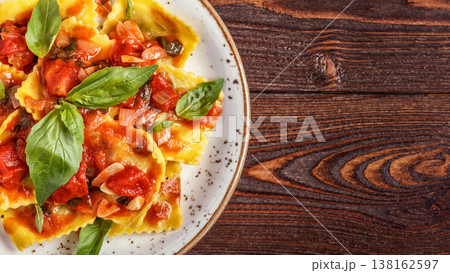 Ravioli with tomato sauce and basil on dark background. Ravioli with tomato sauce and basil on dark background. 138162597