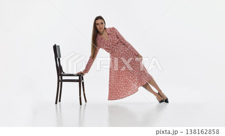 Woman leaning sideways supported by chair isolated on white background. Woman leaning sideways supported by chair isolated on white background. 138162858