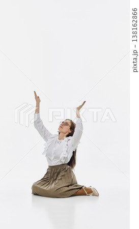 Woman kneeling with raised hands looking up isolated on white background. Woman kneeling with raised hands looking up isolated on white background. 138162866