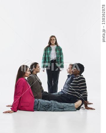 Group sitting on floor facing each other with one woman standing in center isolated on white background Group sitting on floor facing each other with one woman standing in center isolated on white background 138162878