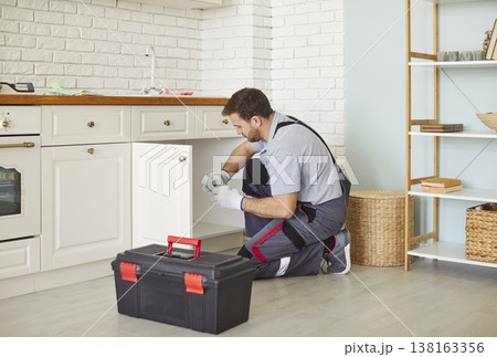 Focused Plumber Fixing Sink In Kitchen Focused Plumber Fixing Sink In Kitchen 138163356