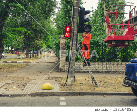 Installation of a traffic light in the city. Electrician worker of electric service company repair traffic lights in city Installation of a traffic light in the city. Electrician worker of electric service company repair traffic lights in city 138164858
