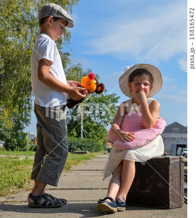 Little children - girl and boy on a railway station, waiting for the train with vintage suitcase. Traveling, holiday and chilhood concept. Travel insurance concept. Travel, tourism, summer vacation Little children - girl and boy on a railway station, waiting for the train with vintage suitcase. Traveling, holiday and chilhood concept. Travel insurance concept. Travel, tourism, summer vacation 138165472