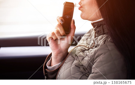 Woman In Car Exhales Into Portable Alcohol Detector. Driver Performs Sobriety Self-Check. Copy space for text Woman In Car Exhales Into Portable Alcohol Detector. Driver Performs Sobriety Self-Check. Copy space for text 138165675