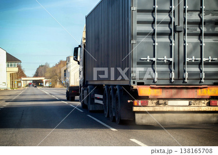 Large semi-trailer truck carrying cargo container on roadside of highway. Freight transport vehicle stopped along asphalt road with markings and clear sky Large semi-trailer truck carrying cargo container on roadside of highway. Freight transport vehicle stopped along asphalt road with markings and clear sky 138165708