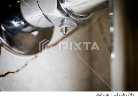 Water droplet forming on underside of polished chrome heated towel rail, water drip against blurred bathroom wall background, close-up shot of water leak. Copy space for text Water droplet forming on underside of polished chrome heated towel rail, water drip against blurred bathroom wall background, close-up shot of water leak. Copy space for text 138165748