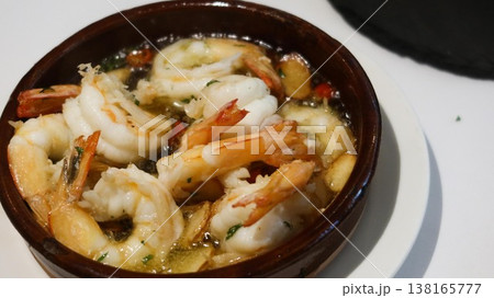 Close-up of Spanish-style traditional tapas garlic shrimp served hot in a brown ceramic bowl with garlic slices and herbs in oil-based sauce with copy space Close-up of Spanish-style traditional tapas garlic shrimp served hot in a brown ceramic bowl with garlic slices and herbs in oil-based sauce with copy space 138165777