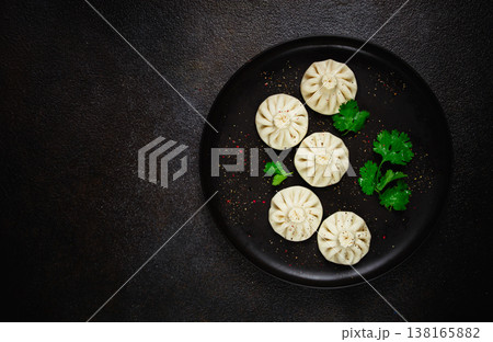 Khinkali, a traditional Georgian dish, with spices and herbs, on a black plate, top view, no people, Khinkali, a traditional Georgian dish, with spices and herbs, on a black plate, top view, no people, 138165882