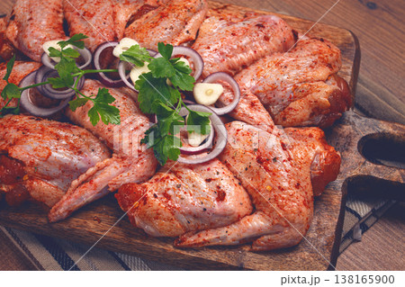 Chicken wings, marinated and laid out on a wooden platter, ready for cooking, grilling or baking, in a home kitchen, there are no people Chicken wings, marinated and laid out on a wooden platter, ready for cooking, grilling or baking, in a home kitchen, there are no people 138165900