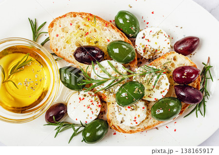 a plate with a snack, ciabatta bread with cheese and olives, olive oil, spices and herbs, top view, no people, a plate with a snack, ciabatta bread with cheese and olives, olive oil, spices and herbs, top view, no people, 138165917