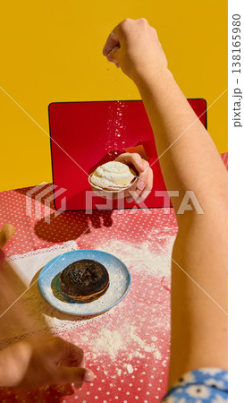 Hand sprinkling flour onto tart emerging from tablet screen on kitchen table Hand sprinkling flour onto tart emerging from tablet screen on kitchen table 138165980