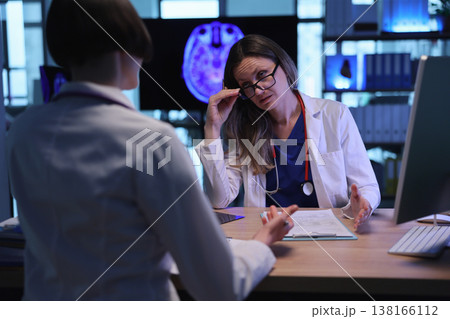 Discussing treatment options in a modern medical office with advanced technology visible in the background Discussing treatment options in a modern medical office with advanced technology visible in the background 138166112