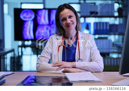 Smiling medical professional in her office reviews patient scans during a calm afternoon 138166116