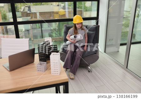 Young architect daydreams in modern office decorated with miniature buildings, while planning future projects in the daylight Young architect daydreams in modern office decorated with miniature buildings, while planning future projects in the daylight 138166199