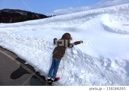 山道にできた深い積雪と雪壁に触れる人 138166265