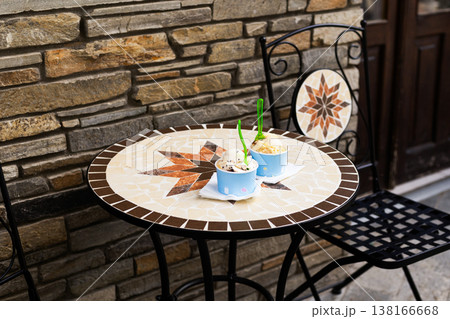 Two paper cups filled with delicious ice cream scoops sitting on a table at an outdoor summer cafe. Refreshing street food concept with blurred background and copy space Two paper cups filled with delicious ice cream scoops sitting on a table at an outdoor summer cafe. Refreshing street food concept with blurred background and copy space 138166668