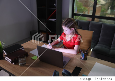 Young girl focused on her creative work at a cozy home office in the evening light Young girl focused on her creative work at a cozy home office in the evening light 138166723