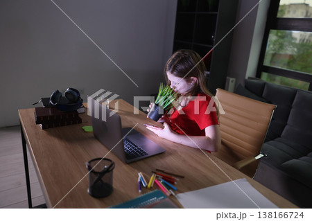 Young girl enjoys quiet moments at home while tending to her plant in a cozy workspace during the evening Young girl enjoys quiet moments at home while tending to her plant in a cozy workspace during the evening 138166724