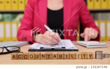 Businesswoman emphasizing responsibility while working at a desk with financial documents and wooden blocks during a productive afternoon Businesswoman emphasizing responsibility while working at a desk with financial documents and wooden blocks during a productive afternoon 138167146