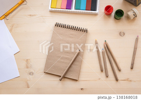 Creative workspace with notebook pencils and art supplies on wooden desk Creative workspace with notebook pencils and art supplies on wooden desk 138168018
