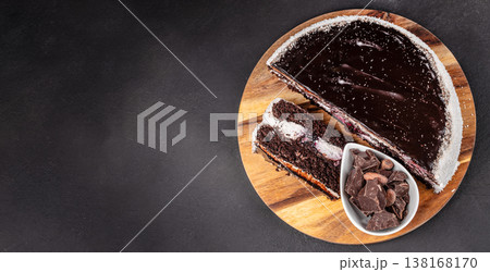 Chocolate cake with slice and dark chocolate on wooden board top view Chocolate cake with slice and dark chocolate on wooden board top view 138168170