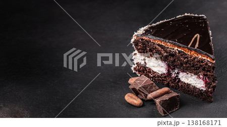 Chocolate cake slice with cocoa beans and chocolate chunks on dark background Chocolate cake slice with cocoa beans and chocolate chunks on dark background 138168171