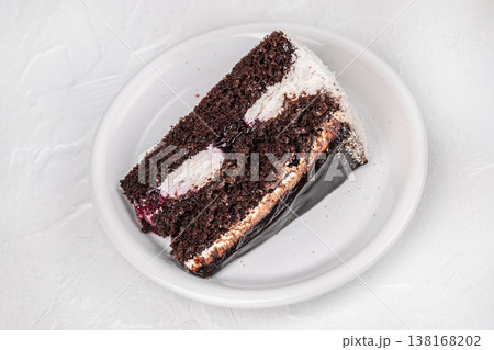 Chocolate cake slice on white plate top view on light background 138168202