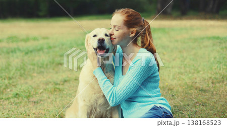 Happy owner woman with Golden Retriever dog sitting on grass together in park Happy owner woman with Golden Retriever dog sitting on grass together in park 138168523