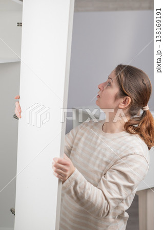 A Caucasian woman assembles a wardrobe. 138169191