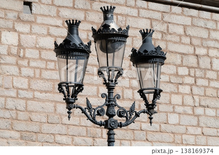 Ornate three lantern street lamp against brick wall Ornate three lantern street lamp against brick wall 138169374