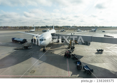 Passenger airplane at airport gate with jet bridge and ground service vehicles Passenger airplane at airport gate with jet bridge and ground service vehicles 138169375