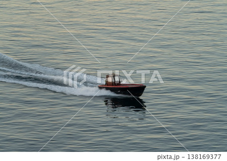 Small motorboat speeding across calm sea with wake Small motorboat speeding across calm sea with wake 138169377