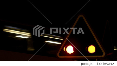 Train signal shows red light during night as train passes by in motion creating light trails 138169842
