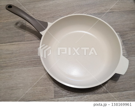 Empty modern frying pan with a ceramic non-stick coating and minimalist design on a wooden surface Empty modern frying pan with a ceramic non-stick coating and minimalist design on a wooden surface 138169961