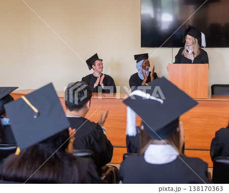 A young woman stands at the lectern and delivers a graduation speech to her classmates.  138170363