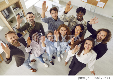 Top view of happy business people alooking at camera and raising hands voting in the office. 138170654