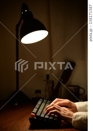 夜リモートワークでキーボードをタイピングする男性の手元 夜リモートワークでキーボードをタイピングする男性の手元 138171387